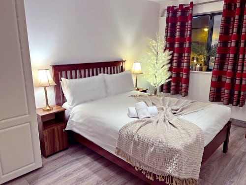 The Liffey Suite bedroom at Dublin Exchange Suites with queen bed, burgundy headboard, white linens, and red striped