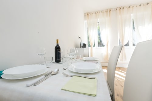 Eleganter Esstisch mit weißen Tellern, Weingläsern und Weinflasche in Magnolia Apartments Mailand Zimmer 18B