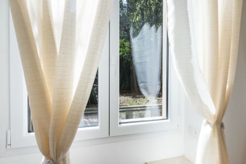 Helle creme Gardinen rahmen die Gartenaussicht in den Magnolia Apartments Mailand ein und zeigen natürliches Licht und Grünflächen