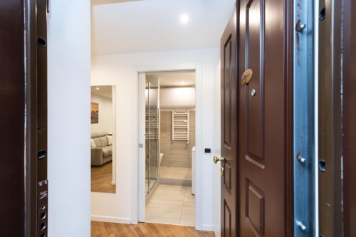 Moderner Flur in Magnolia Apartments Milan mit weißen Türen zu Bad und Wohnbereich, Holzfußboden und Brauntönen
