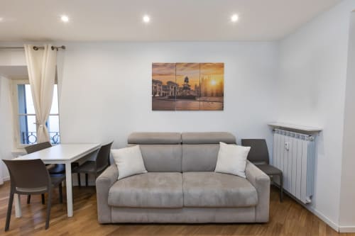 Modernes Wohnzimmer in Mailand mit grauem Sofa, Esstisch und Kunstwerk mit Stadtlandschaft bei Sonnenuntergang