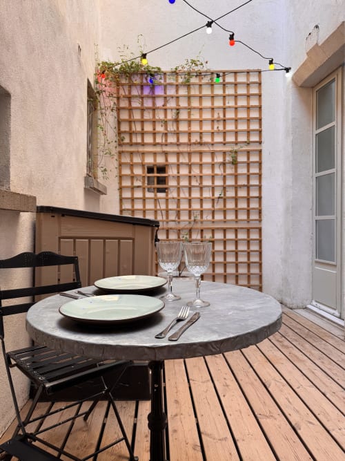 Intimate courtyard dining setup at Mes à Moi Pézenas with round marble table, place settings, and wooden trellis backdrop