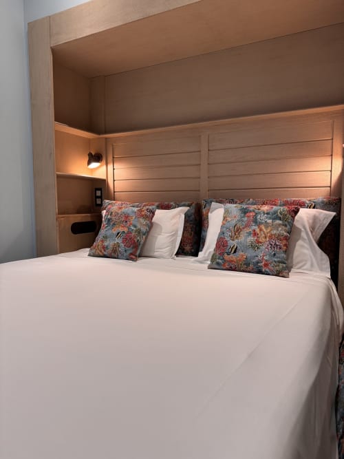 Modern bedroom in Mes à Moi Pézenas with white bedding, decorative pillows, wooden headboard, and warm lighting