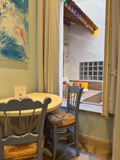 Dining area in O Pitchoun apartment at Mes à Moi Pézenas with table, chair, and view into bedroom courtyard