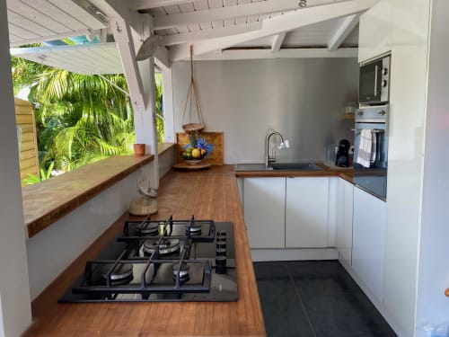 Cuisine de charme moderne avec cuisinière au gaz, placards blancs, comptoirs en bois et vue sur le jardin aux Villas aux Antilles,