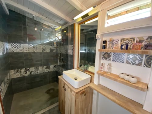 Salle de bains moderne de la villa aux Antilles avec douche italienne, vasque blanche, meuble en bois et carrelage décoratif