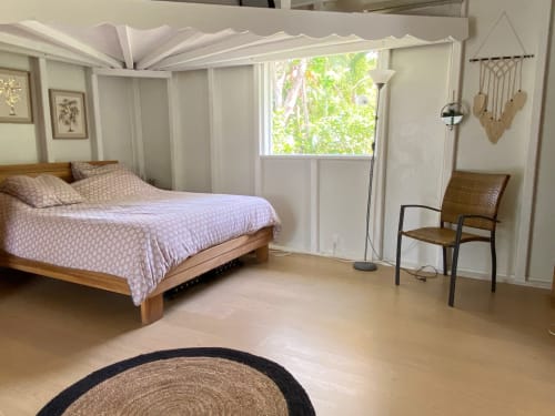 Chambre lumineuse avec vue sur le jardin aux Villas aux Antilles, lit en bois, baldaquin blanc, fauteuil tressé et lumière naturelle