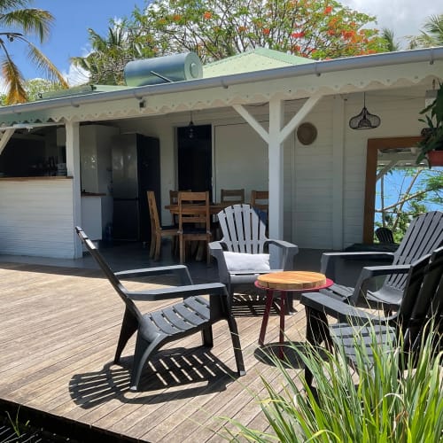 Terrasse de cottage aux Villas aux Antilles avec fauteuils Adirondack, table en bois et vue sur le jardin à Saint-François