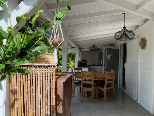 Salle à manger cottage moderne avec mobilier en bois, plantes suspendues et poutres apparentes aux Villas aux Antilles