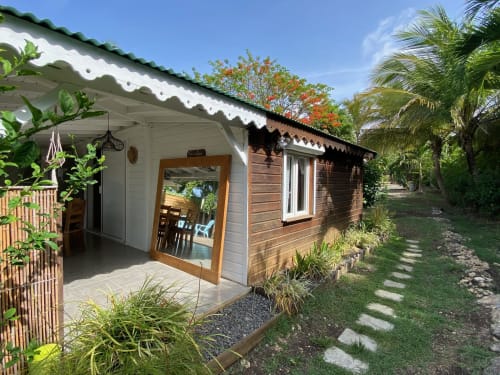 Petit cottage de jardin aux Villas aux Antilles à Saint-François avec véranda couverte, portes en bois, paysagisme tropical et palmiers