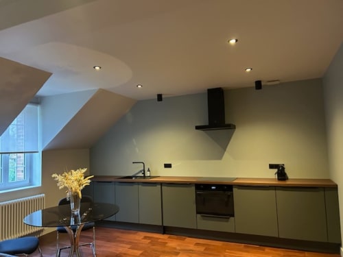 Modern attic kitchen in Primat apartment at Le Petit Château, Baye with wood counters, yellow walls, dining area, and garden