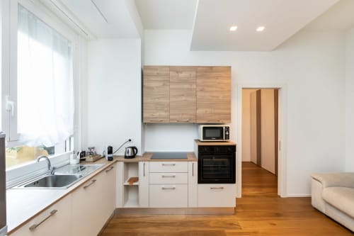 Moderne Küche in Magnolia Apartments Milan mit weißen Schränken, Holzarbeitsplatten, Edelstahlspüle und schwarzem Ofen
