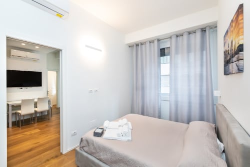 Modernes Schlafzimmer in der Magnolia Apartments Mailand mit Bett, Gartenblick-Vorhängen und Zugang zum Wohnbereich