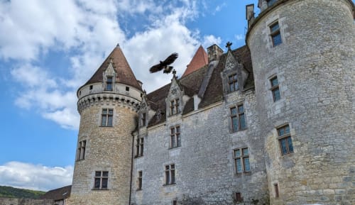 Medieval castle towers at Domaine De Campagnac B&B in Carsac-Aillac, France with stone walls and turrets under blue sky