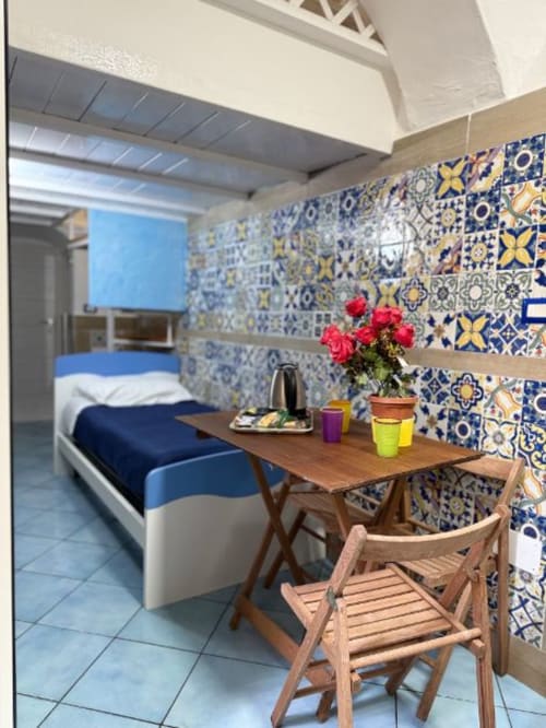 Camera moderna della San Nicola Suite Mini Apartments a Sorrento con parete decorativa in maiolica blu e gialla, scrivania in legno e