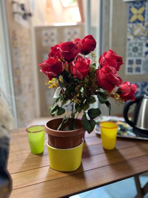 Rose rosse vivaci in vaso giallo su tavolo in legno presso la San Nicola Suite, appartamento a Sorrento con vista sulla città
