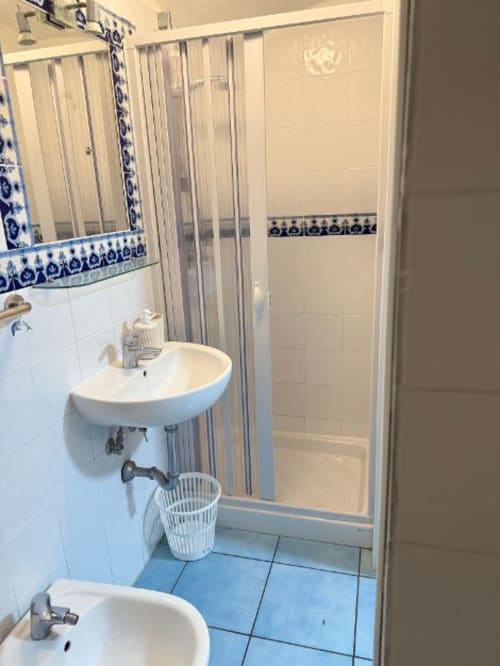 Bagno della San Nicola Suite Mini Apartments a Sorrento con doppio lavabo, doccia e pavimento in piastrelle blu