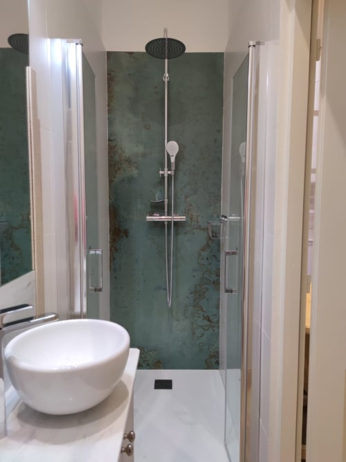 Modern bathroom with white toilet, rainfall showerhead, and green-tiled walk-in shower at Mes à Moi Pézenas apartment in