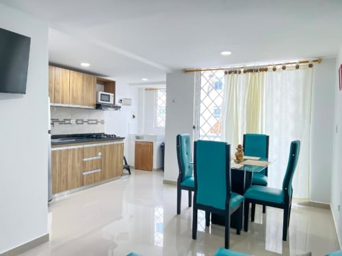 Moderna cocina y comedor con sillas turquesas en el apartamento hotel Olamar Living de Santiago de Tolú