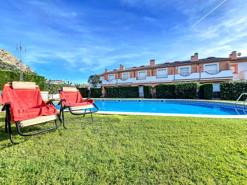 Tumbonas rojas en el césped con vistas a la piscina azul de la casa rural La Bella Lola en L'Estartit, España
