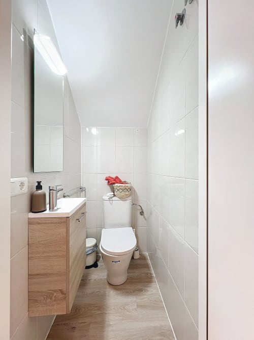 Baño moderno con azulejos blancos, tocador de madera, inodoro y lavabo en la casa rural La Bella Lola en L'Estartit