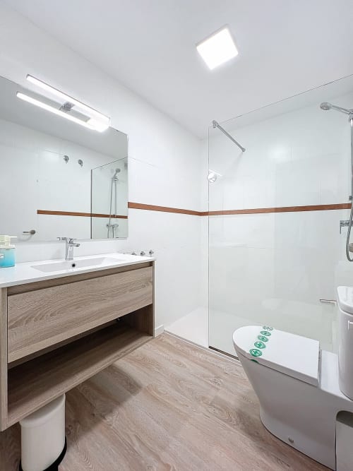 Baño moderno de la casa rural La Bella Lola en Estartit con azulejos blancos, detalles de madera y ducha abierta