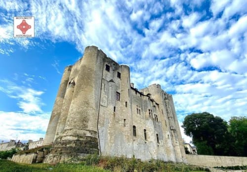 Tour en pierre historique aux murs usés sous un ciel bleu, près des Marais Poitevin à Cram-Chaban, France.