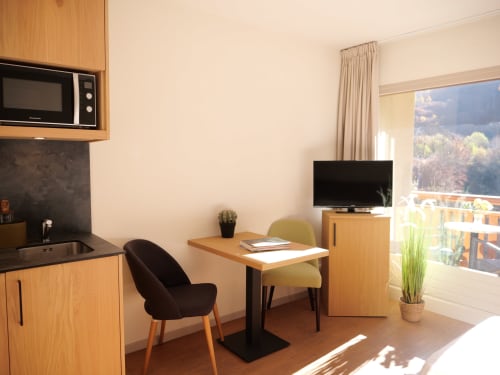 Studio moderne à Hôtel Studios La Rochetaillée avec kitchenette, espace de travail, TV et vue sur les montagnes depuis le balcon