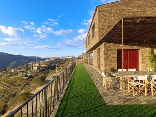 Quinta Do Fraguil terrace with green lawn, wooden seating, red door, and Douro Valley views