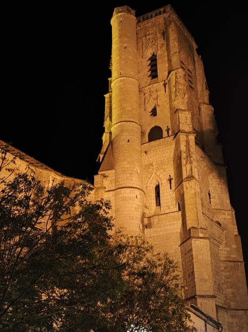 Historic stone church tower illuminated at night in Saint-Puy, near Le Rêve d'Alice bed and breakfast