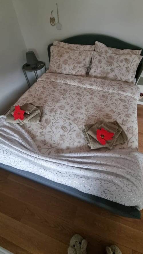 Camera accogliente della Maso Kreuzberg B&B a Trento con biancheria floreale e cuscini decorativi rossi