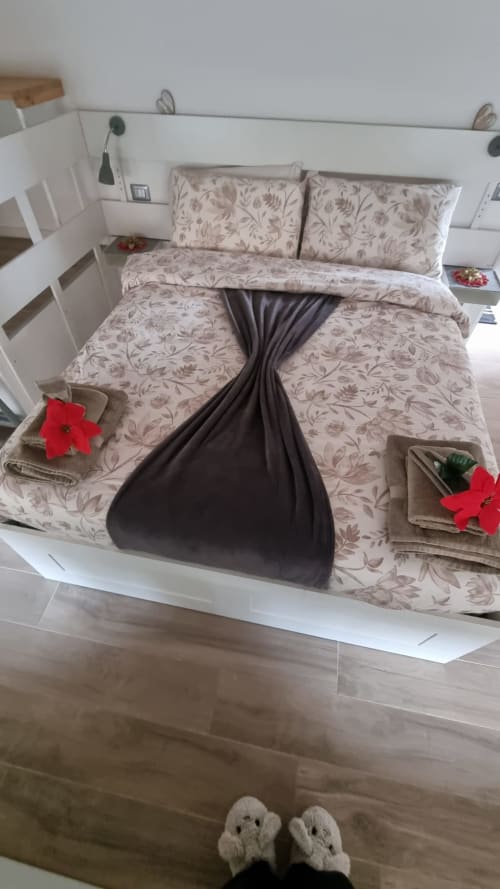 Camera accogliente al Maso Kreuzberg BnB di Trento con biancheria floreale, cuscini decorativi e atmosfera montana