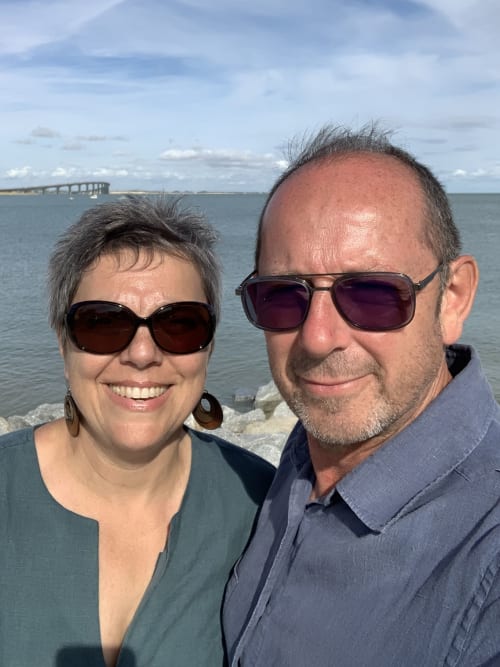 Couple souriant sur la plage côtière avec pont en arrière-plan, région Marais Poitevin en France