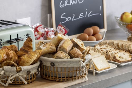 Petit-déjeuner à l'Hôtel De Lion Sur Mer avec croissants, pain, œufs et pâtisseries sur un comptoir en bois