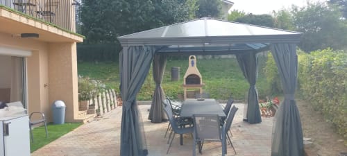 Terrasse extérieure du Gîte des Gônes avec pergola, table à manger et four à pizza en bois à Feyzin