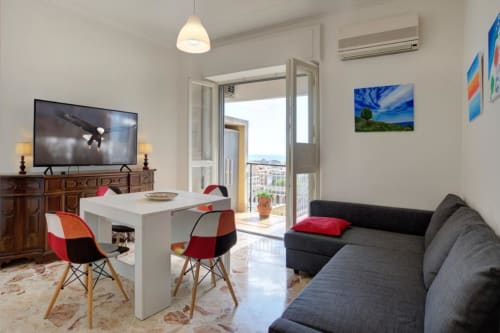 Moderno soggiorno dell'Aparthotel Bentivoglio Catania con divano, zona pranzo, TV e vista dal balcone