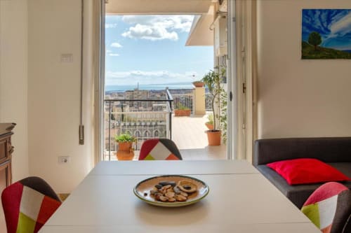 Appartamento a Catania con balcone-terrazza, vista sul mare, tavolo da pranzo con snack e cuscini colorati