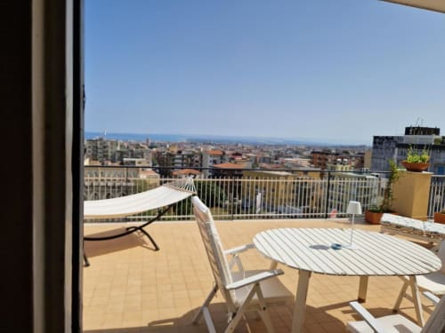 Terrazza sul tetto dell'Aparthotel Bentivoglio con vista panoramica sulla città di Catania, arredamento bianco e cielo blu sereno