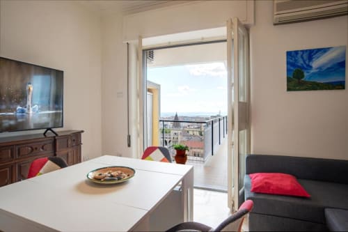 Moderno appartamento all'Aparthotel Bentivoglio Catania con balcone, vista, tavolo da pranzo, TV e divano con cuscini rossi