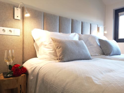 Quarto moderno do hotel Em Xisto em Góis com cabeceira estofada, roupa de cama branca e rosas vermelhas na mesa de cabeceira