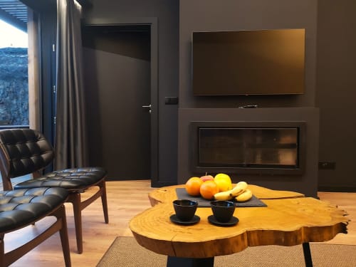 Sala de estar moderna do hotel Em Xisto com mesa de madeira, lareira, TV e vista para as montanhas em Góis, Portugal