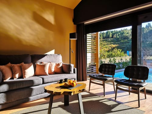 Lounge moderno do hotel Em Xisto em Góis com paredes ocre, sofá cinzento e vistas de paisagem montanhosa e piscina