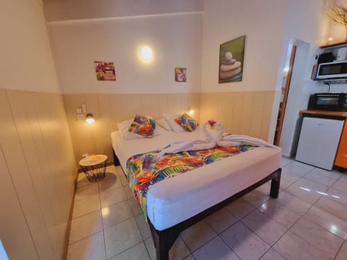 Colorful studio bedroom at Gites Kaladja in Port-Louis with double bed, kitchenette, ambient lighting, and modern amenities