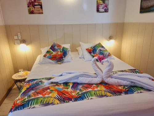 Colorful tropical-themed double bed at Gites Kaladja studio in Port-Louis with decorative towel swans and vibrant patterned