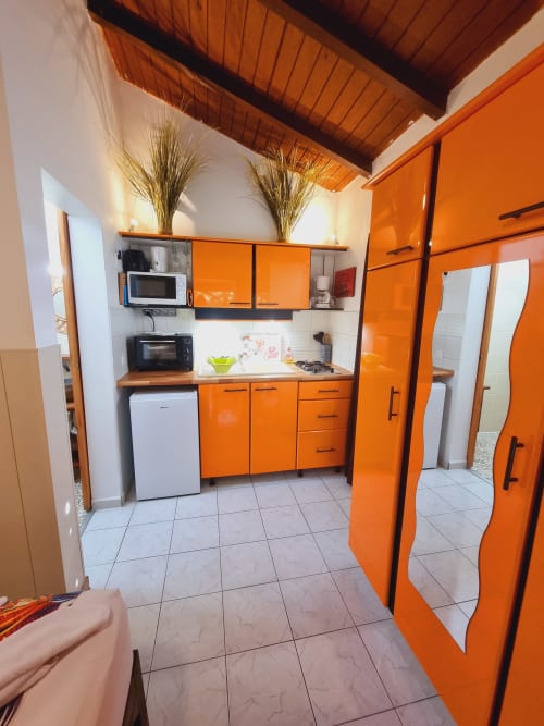 Bright orange kitchen in Graj studio at Gites Kaladja, Port-Louis, featuring modern appliances and wooden ceiling