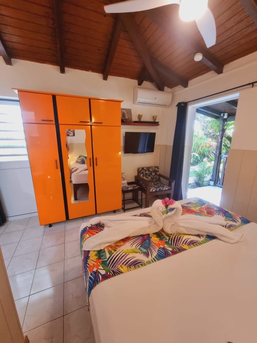 Modern studio bedroom at Gites Kaladja with orange wardrobe, colorful bedding, and garden view in Port-Louis, Guadeloupe