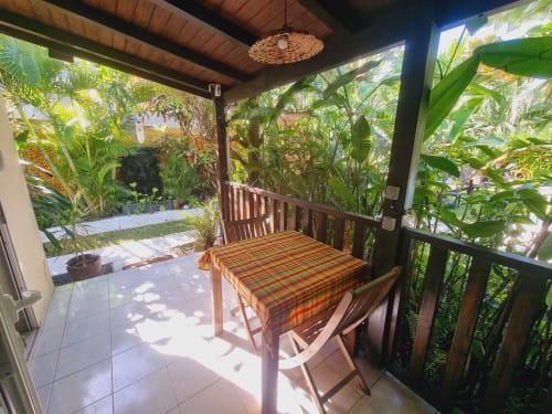 Covered outdoor dining area at Gites Kaladja with table, chairs, and lush tropical garden views in Port-Louis