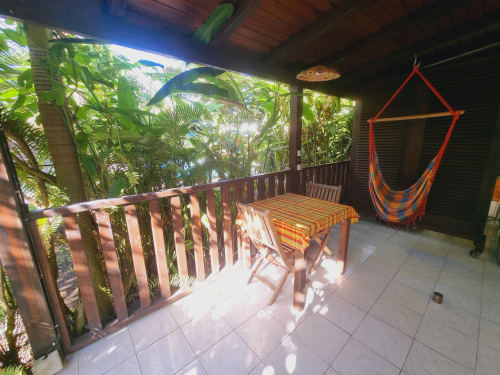 Tropical patio at Gites Kaladja in Guadeloupe with dining table, colorful hammock, and lush vegetation views