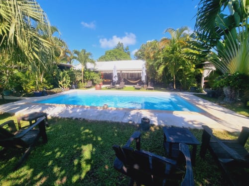 Tropical pool area at Gites Kaladja in Guadeloupe with palm trees, loungers, and white guest house