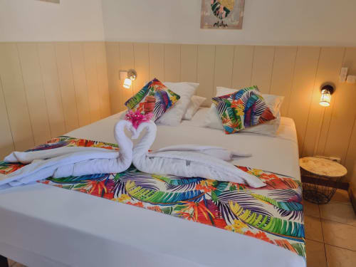 Padjambel studio at Gites Kaladja with colorful tropical bedding, white towel swans, pink flower, and ambient lighting in